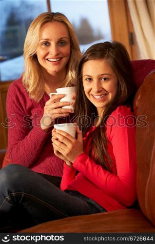 Portrait Of Mother And Daughter Relaxing On Sofa Together With Hot Drink