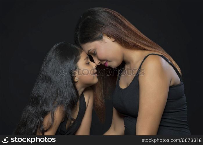 Portrait of mother and daughter touching foreheads