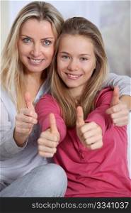 Portrait of mother and daughter with thumbs up