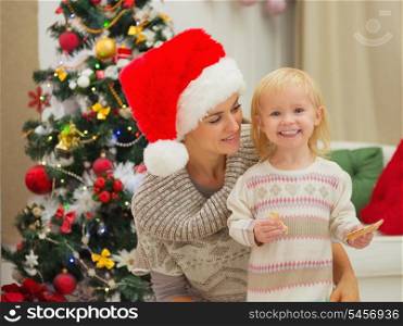 Portrait of mother and happy eat smeared baby near Christmas tree