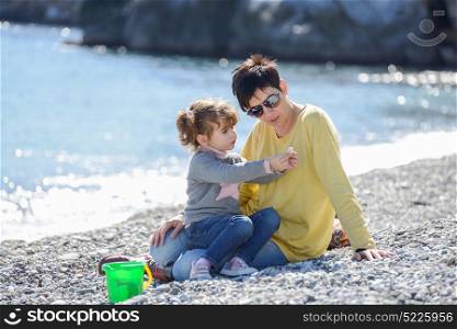 Portrait of mother and her little daughter having fun on the beach