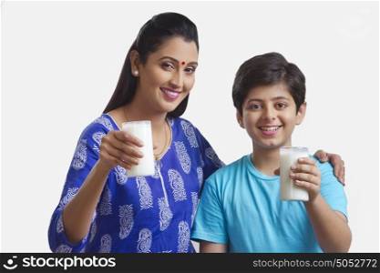 Portrait of mother and son holding glass of milk