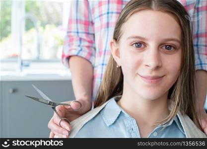 Portrait Of Mother Cutting Teenage Daughters Hair At Home During Lockdown