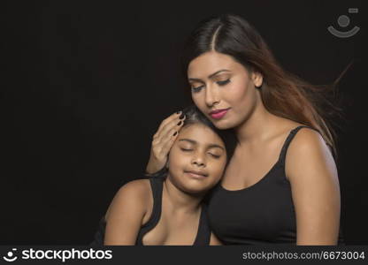 Portrait of mother embracing daughter eyes closed