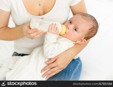 Portrait of mother feeding her 3 months old baby from bottle