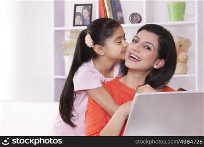 Portrait of mother getting kiss from daughter