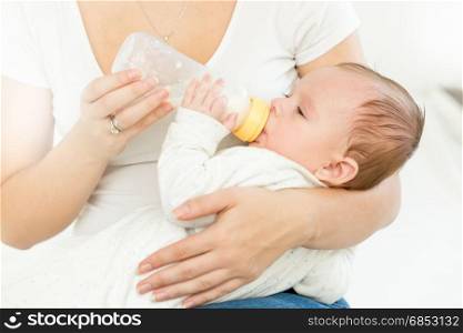 Portrait of mother giving milk from bottle to her baby