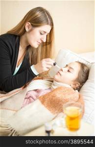 Portrait of mother giving nasal medicines to sick daughter lying in bed