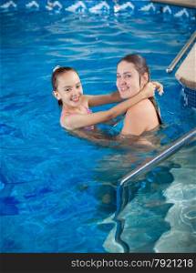 Portrait of mother holding daughter on water surface and teaching how to swim