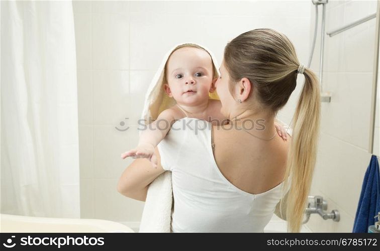 Portrait of mother holding her baby in towel at bathroom
