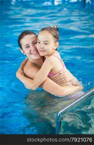 Portrait of mother hugging daughter in swimming pool