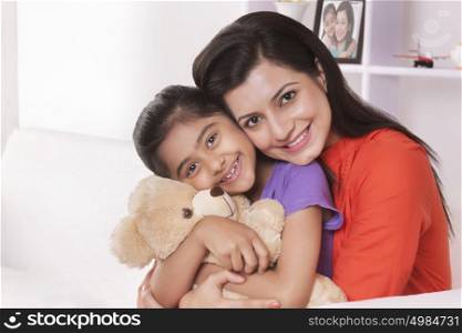 Portrait of mother hugging daughter with stuffed toy