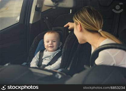 Portrait of mother looking at baby sitting on car front seat