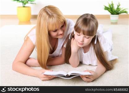 portrait of mother together with daughter with book in studio