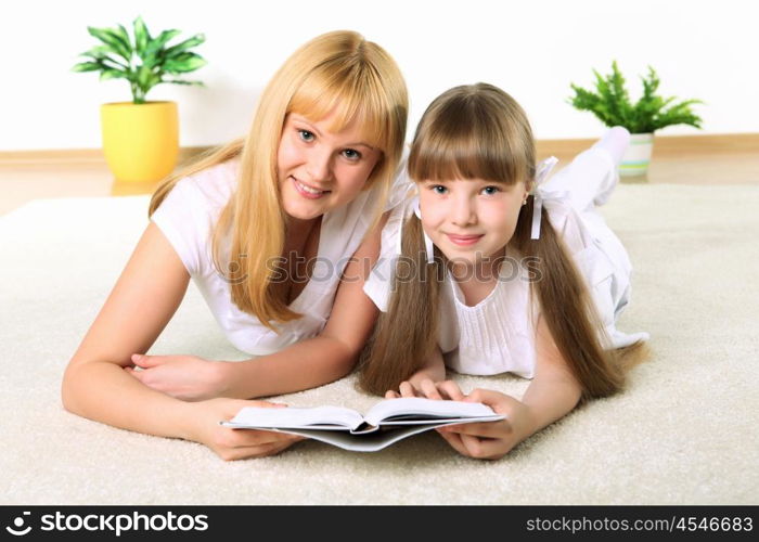 portrait of mother together with daughter with book in studio