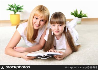 portrait of mother together with daughter with book in studio