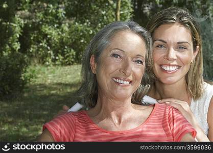 Portrait of mother with adult daughter in garden, smiling, close-up