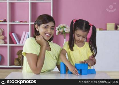 Portrait of mother with daughter playing shaping blocks at table