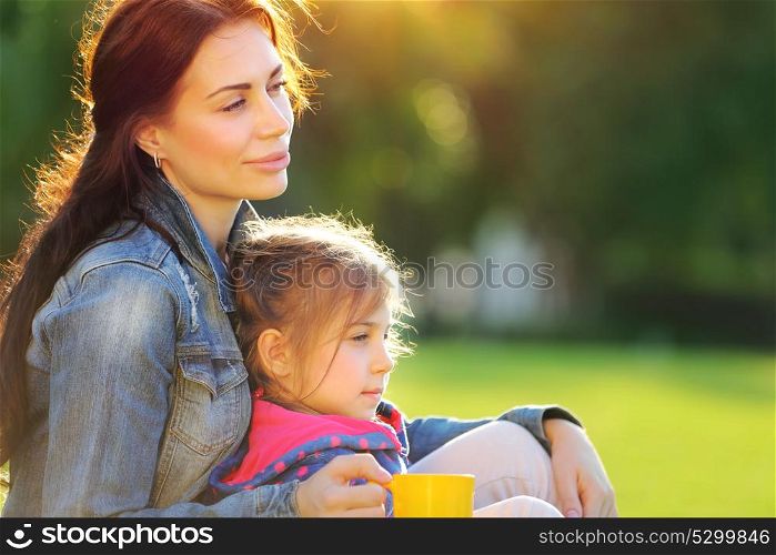 Portrait of mother with daughter relaxing outdoors, spending time together in warm sunny autumn day, loving happy family