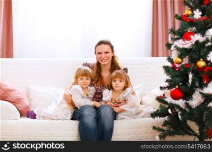 Portrait of mother with two twins daughters near Christmas tree&#xA;