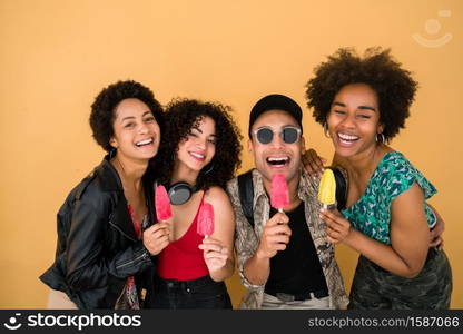 Portrait of multi-ethnic group of friends having fun and enjoying summertime while eating ice cream against yellow background.