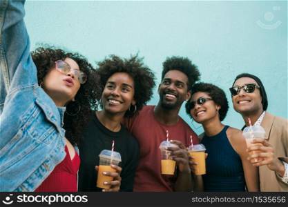 Portrait of multi-ethnic group of friends having fun together and taking a selfie while drinking fresh fruit juice.