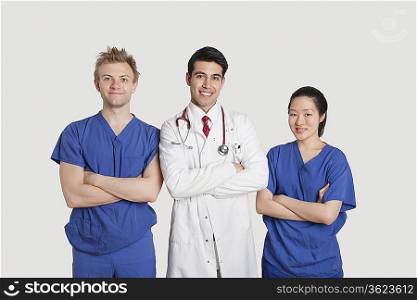 Portrait of multi ethnic healthcare professionals standing with arms crossed over gray background