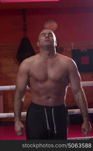 portrait of muscular professional kickboxer who standing in the ring while training for the fight