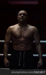 portrait of muscular professional kickboxer who standing in the ring while training for the fight