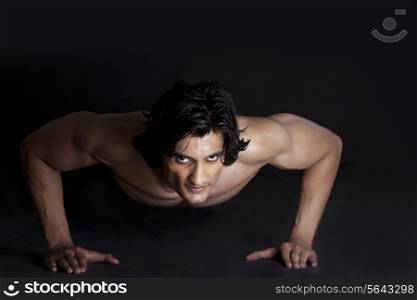 Portrait of muscular young man stretching against black background