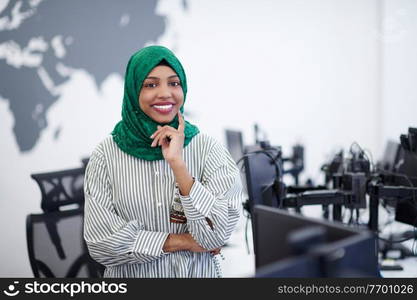 Portrait of muslim african female software developer with green hijab standing at modern open plan startup office