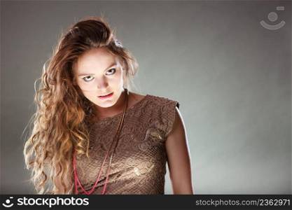 Portrait of mysterious enigmatic woman in studio on grey. Young intriguing attractive girl with long curly hair. Shining light.. Mysterious enigmatic attractive woman girl.