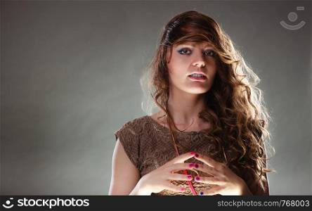Portrait of mysterious enigmatic woman in studio on grey. Young intriguing attractive girl with long curly hair. Shining light.. Mysterious enigmatic attractive woman girl.