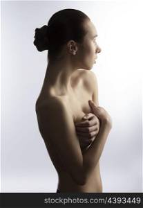 portrait of naked sexy woman with chignon hair-style she covering her breast with hands