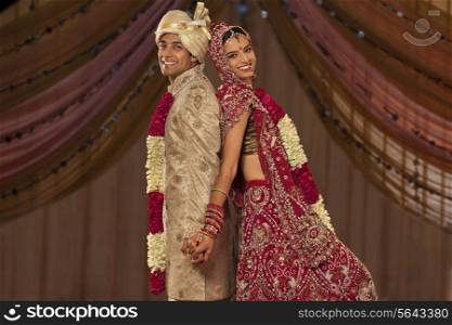 Portrait of newly married Indian couple holding hands