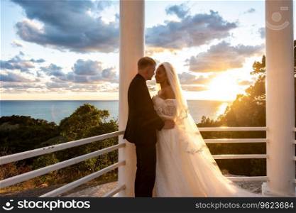 Portrait of newlyweds in a gazebo with columns in the rays of the setting sun a. Portrait of newlyweds in a gazebo with columns in the rays of the setting sun