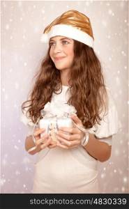 Portrait of nice teen girl holding in hands festive gift box and looking on the side, little Santa Claus helper, Christmas time magic concept