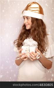 Portrait of nice teen girl holding in hands festive gift box and looking on the side, little Santa Claus helper, Christmas time magic concept