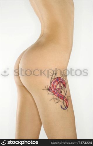 Portrait of nude attractive redhead Caucasian young woman with lizard tattoo.
