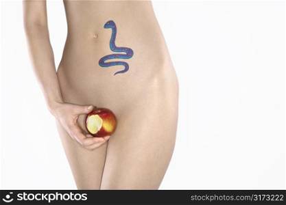 Portrait of nude attractive redhead Caucasian young woman with snake tattoo holding apple.