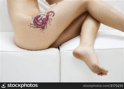 Portrait of nude attractive redhead Caucasian young woman with tattoo.