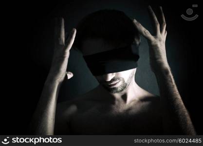 Portrait of nude blindfolded young man on a black background