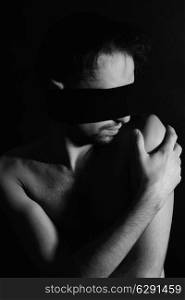 Portrait of nude young man blindfolded on a black background