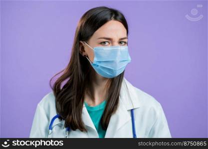 Portrait of nurse in protective medical mask and coat disapproving with no head gesture. Denying, Rejecting, Disagree, Portrait of female doctor on violet background. High quality photo. Portrait of nurse in protective medical mask and coat disapproving with no head gesture. Denying, Rejecting, Disagree, Portrait of female doctor on violet background