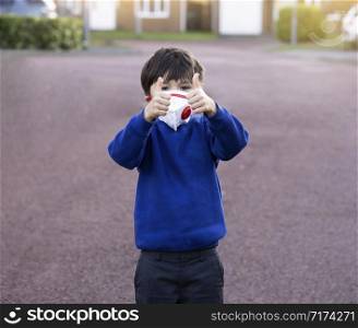 Portrait of of School kid wearing protective face mask for pollution or virus, Child in school uniform wearing protection mask and showing thumbs up while waiting for school bus in the morning.