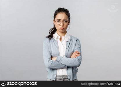 Portrait of offended insecure and timid cute asian girl complaining on cruel customer being rude to her, cross hands over chest defensive and upset, frowning gloomy, feel upset grey background.. Portrait of offended insecure and timid cute asian girl complaining on cruel customer being rude to her, cross hands over chest defensive and upset, frowning gloomy, feel upset grey background