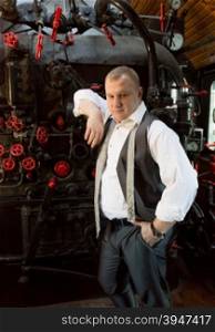 Portrait of old fashion businessman posing at locomotive furnace