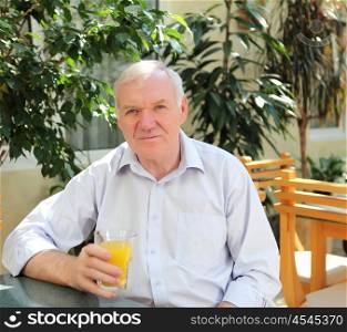 portrait of old man with orange juice outdoors