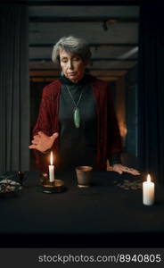 Portrait of old mature gypsy witch standing at table with psychic tools in mystical atmosphere. Portrait of old mature gypsy witch standing at table with psychic tools