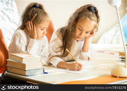 Portrait of older sister explaining homework to younger